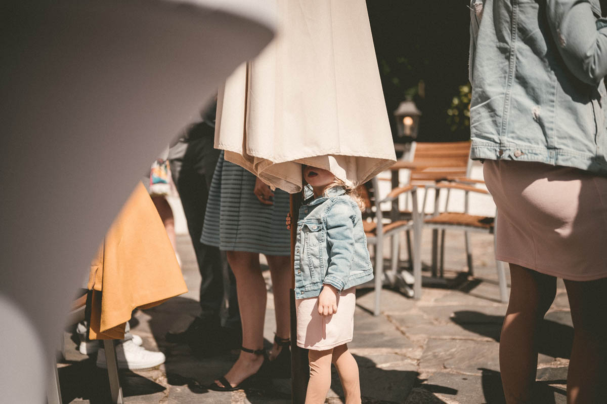 Ein Kind versteckt sich unter einem Sonnenschirm